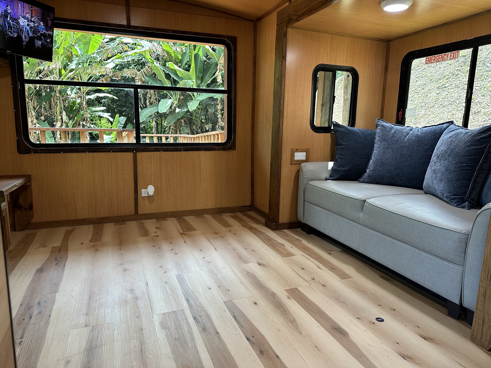 Casa Bambú living area with sofa, smart TV, and a large window over tropical greenery